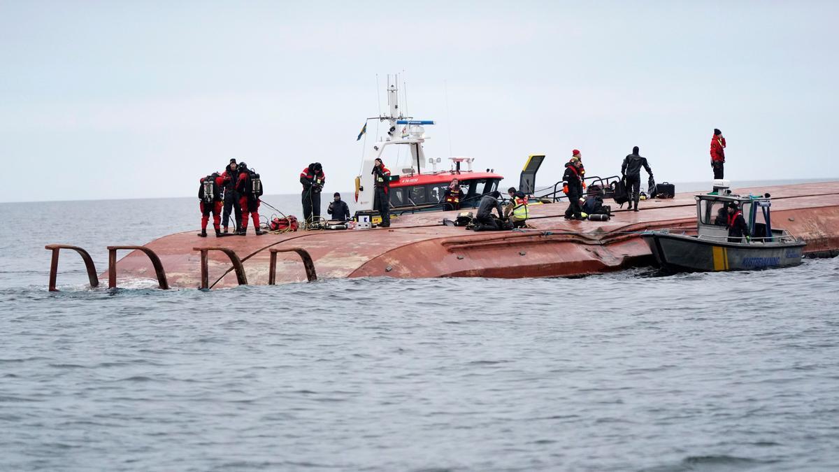 Integrantes de los servicios de rescate sobre el costado del barco danés