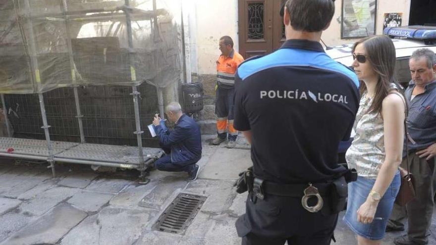 Un técnico municipal toma una foto del inmueble de la calle Damas, en presencia de un policía local.