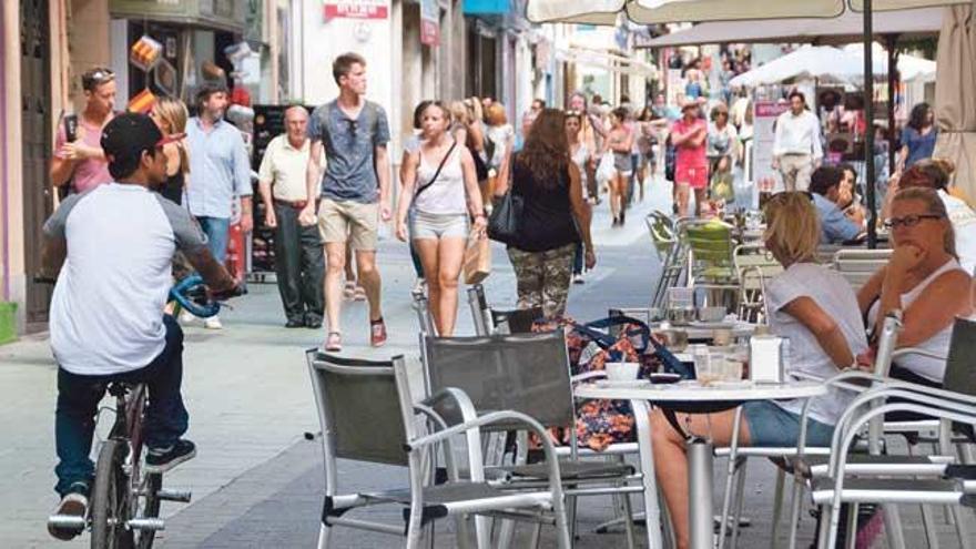 Un ciclista con una bicicleta modificada para llevar más pasajeros circula por una concurrida calle Oms.