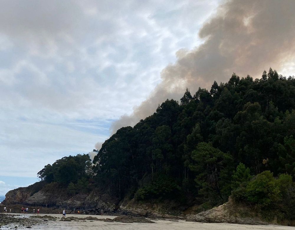 Columna de humo visible desde la playa de Veigue, en Sada, esta mañana.