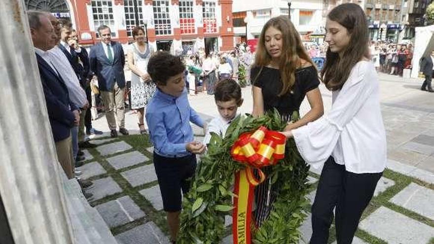 Arriba, cuatro niños colocan una corona en nombre de la familia Jovellanos. Sobre estas líneas, las representantes de la asociación &quot;Gigia&quot; de Cimadevilla entregan su ramo a los pies de la escalera al no poder subir con los carritos de los bebés que las acompañaban.