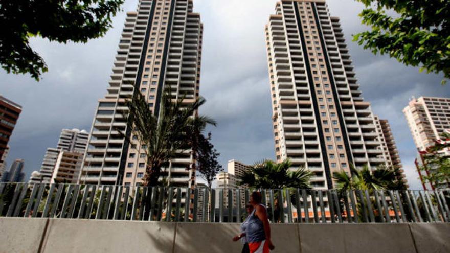 Una pareja de turistas observa la majestuosidad de dos torres de apartamentos construidas en Benidorm que hoy funcionan como apartotel al no haberse vendido.