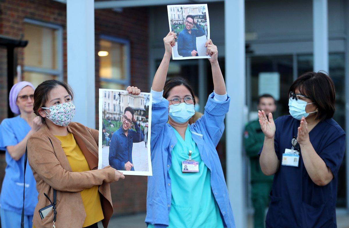 LONDON, ENGLAND  - APRIL 30: Medical workers hold up pictures of their friend and colleague Ken Lambatan who died of COVID-19 as they ’Clap for Our Carers’ outside Kingston Hospital on April 30, 2020 in London, England United Kingdom. Following the success of  the Clap for Our Carers campaign, members of the public are being encouraged to applaud NHS staff and other key workers from their homes at 8pm every Thursday. The Coronavirus (COVID-19) pandemic has infected over 3 million people across the world, claiming at least 26,711 lives in the U.K. (Photo by Chris Jackson/Getty Images) ***BESTPIX***