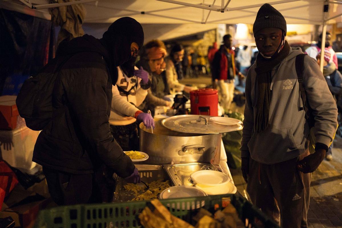Voluntarios de distintas entidades privadas reparten comida para la cena de Nochebuena a los asentados bajo la autopista C-31
