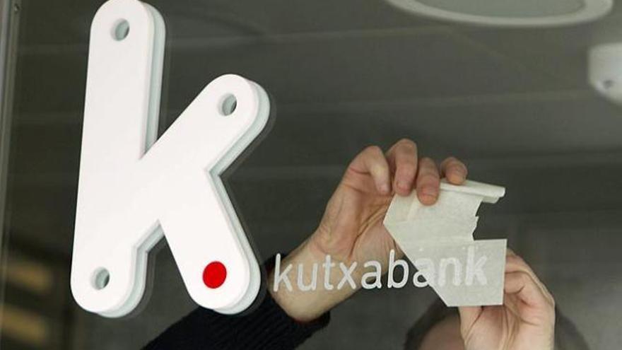 Un operario coloca en una oficina de Vital Kutxa en Vitoria el rótulo con el logotipo de Kutxabank.