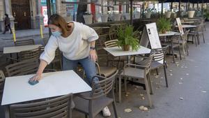 Una mujer repasa las mesas de una terraza en Rambla de Catalunya.