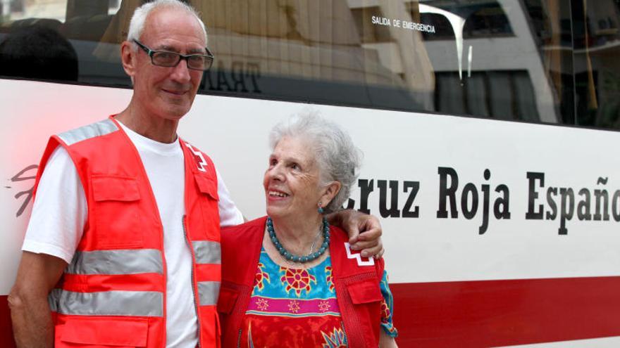 Gigliola mira a Alfredo mientras este la abraza frente a un autobús de la Cruz Roja.