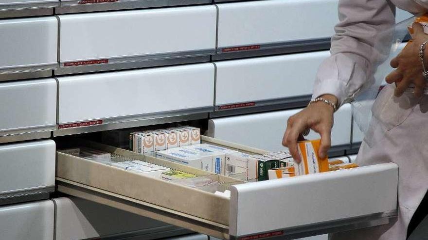 Una farmacéutica clasifica medicamentos en su establecimiento.