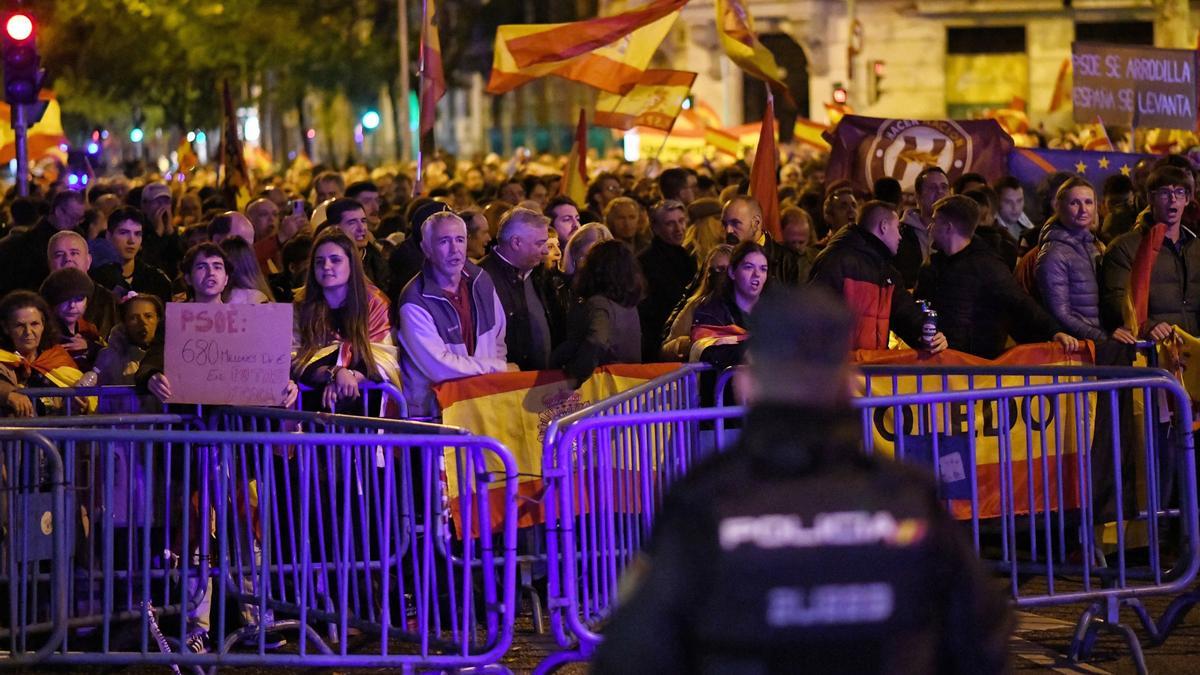 Decenas de personas con banderas y carteles, durante una protesta contra la amnistía, frente a la sede del PSOE, a 11 de noviembre de 2023, en Madrid (España).
