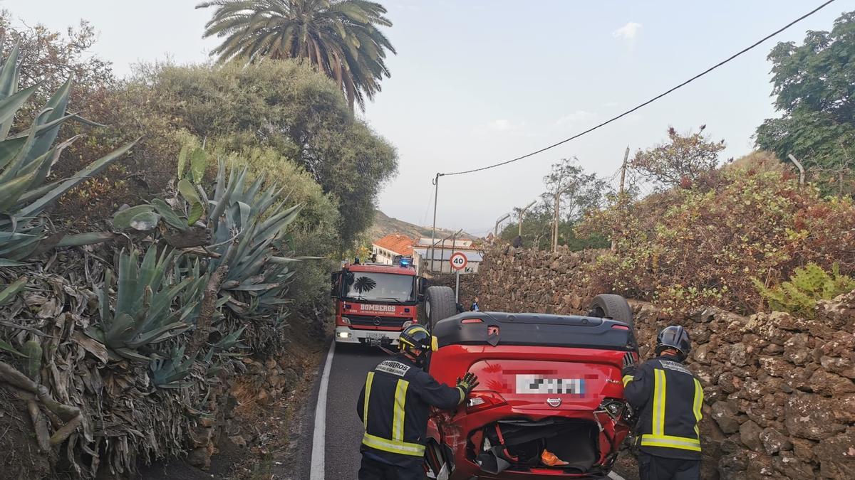 Dos bomberos de la capital grancanaria junto al vehículo que sufrió el accidente en Bandama.