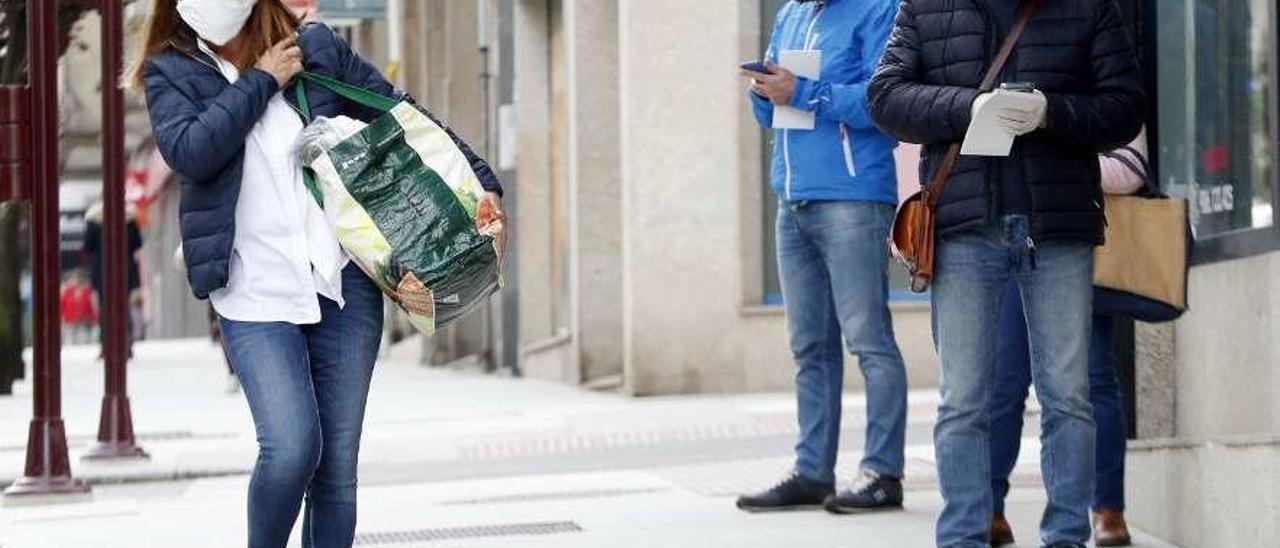 Varias personas, paseando con mascarilla, en una calle de Vigo. // José Lores