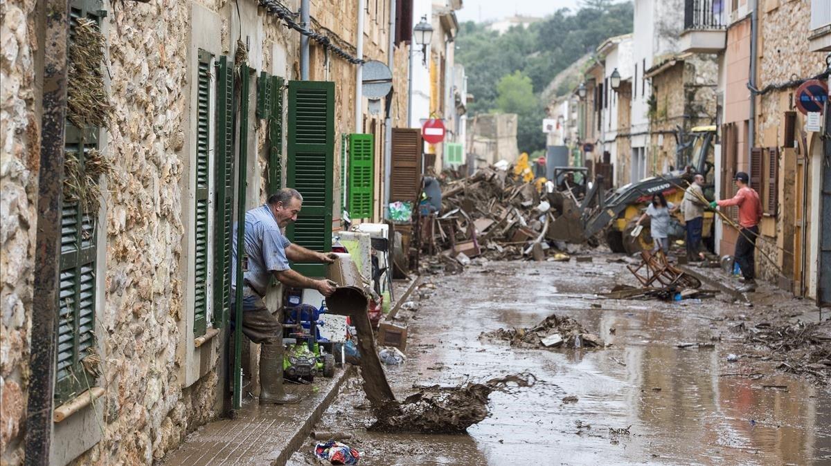 Vecinos de la localidad mallorquina de San Llorenc tratan de quitar el barro y el agua acumulados en las casas y las calles a causa de las inundaciones del martes.