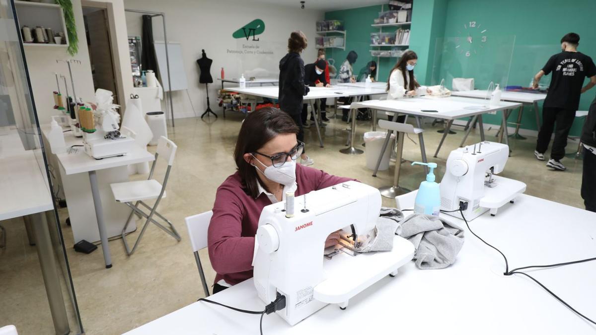 Victoria López, en primer plano, en su escuela de patronaje y confección, en la calle Carmen, mientras unos alumnos asisten a uno de los talleres semanales.