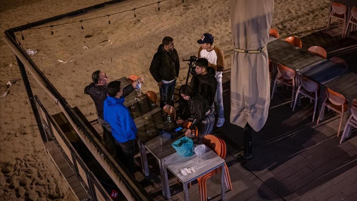 Barcelona 04 04 2021 Barcelona  Botellon i ambiente en la Barceloneta sobre las 21 00h  Grupo de jovenes bebiendo en unas mesas de una terraza de un restaurante cerrado por las restricciones  Barceloneta   AUTOR  Manu Mitru