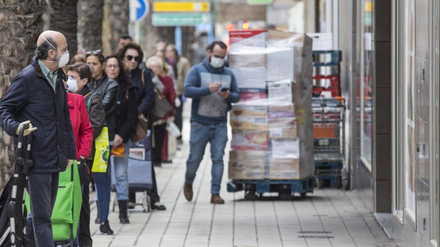 Público haciendo cola para entrar a un supermercado hoy en Alicante