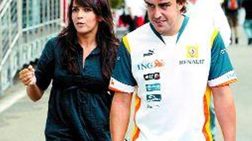 Alonso pasea por el paddock con su pareja, Raquel del Rosario. / Efe
