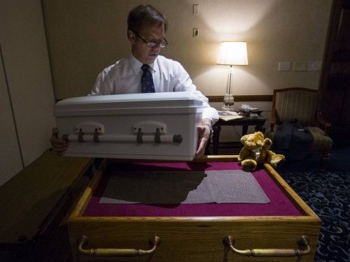 El director de una funeraria levanta el ataúd que contiene los restos de un bebé recién nacido abandonado en una mesa