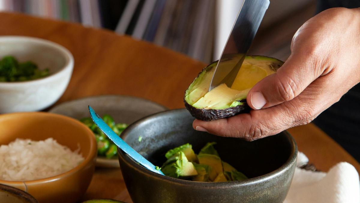 Una persona trocea un aguacate en un bol.