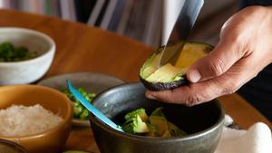 Una persona trocea un aguacate en un bol.