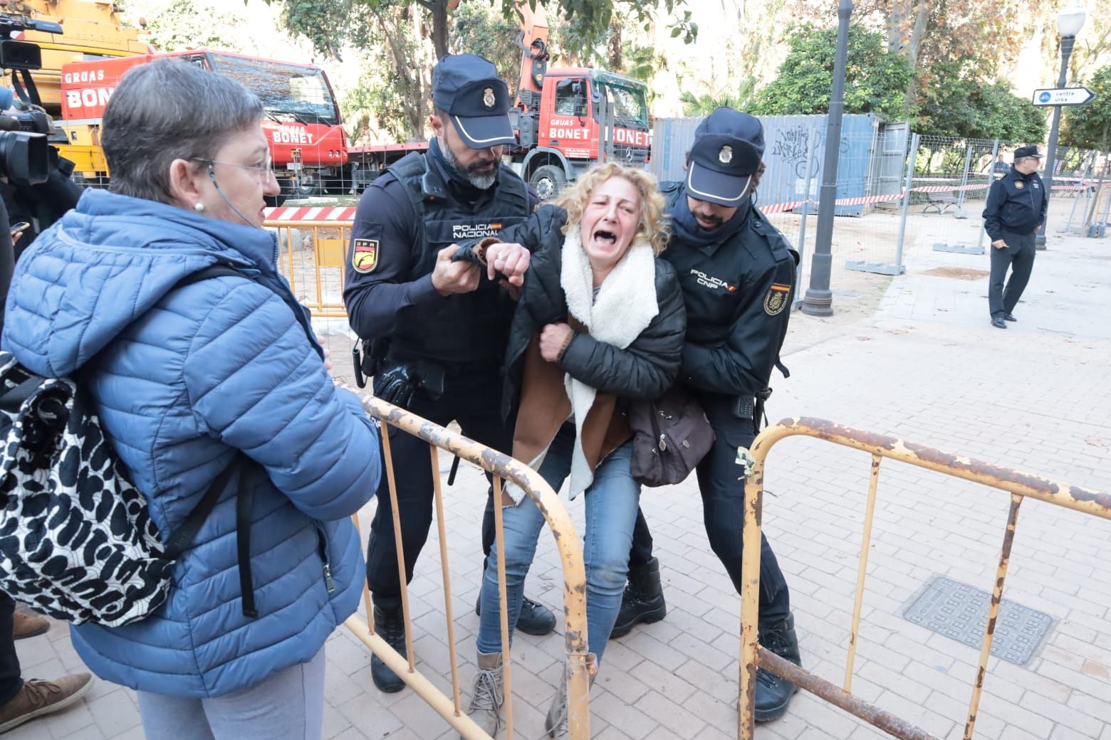 Una señora entra en el recinto vallado y es retirada por agentes de la Policía Nacional.