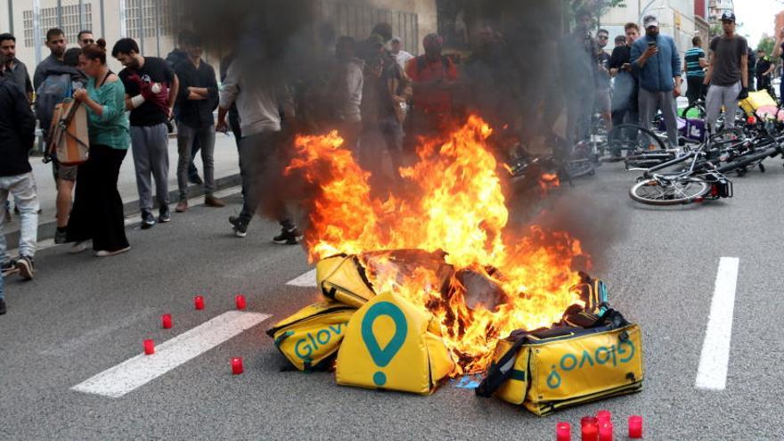 Diversos cistells de Glovo cremant davant d&#039;una de les seus de l&#039;empresa a Barcelona, al carrer on ha tingut una concentració