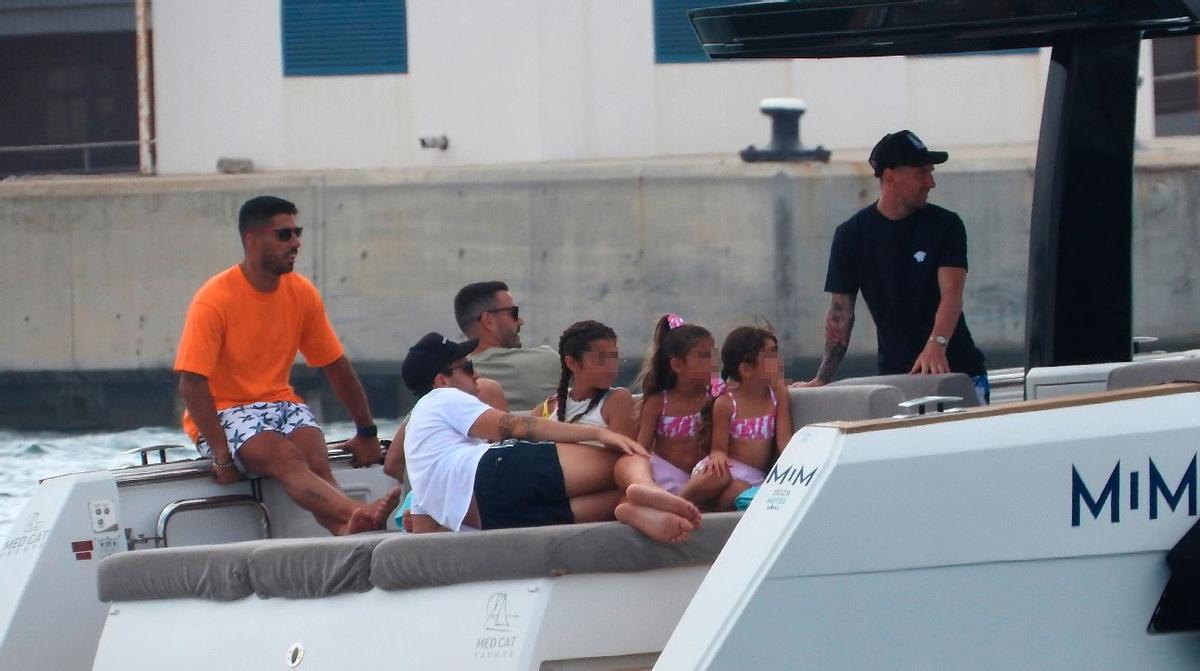 Luis Suárez (izquierda, de naranja), Cesc y Messi (derecha del todo) navegan por aguas de Eivissa con sus familias, este viernes.