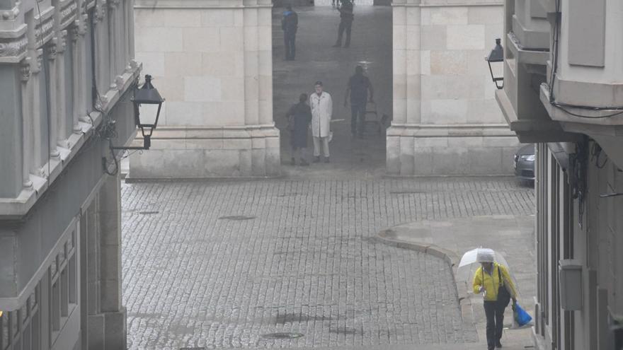 Personas se refugian de la lluvia en los soportales de la plaza de María Pita. |   // CARLOS PARDELLAS