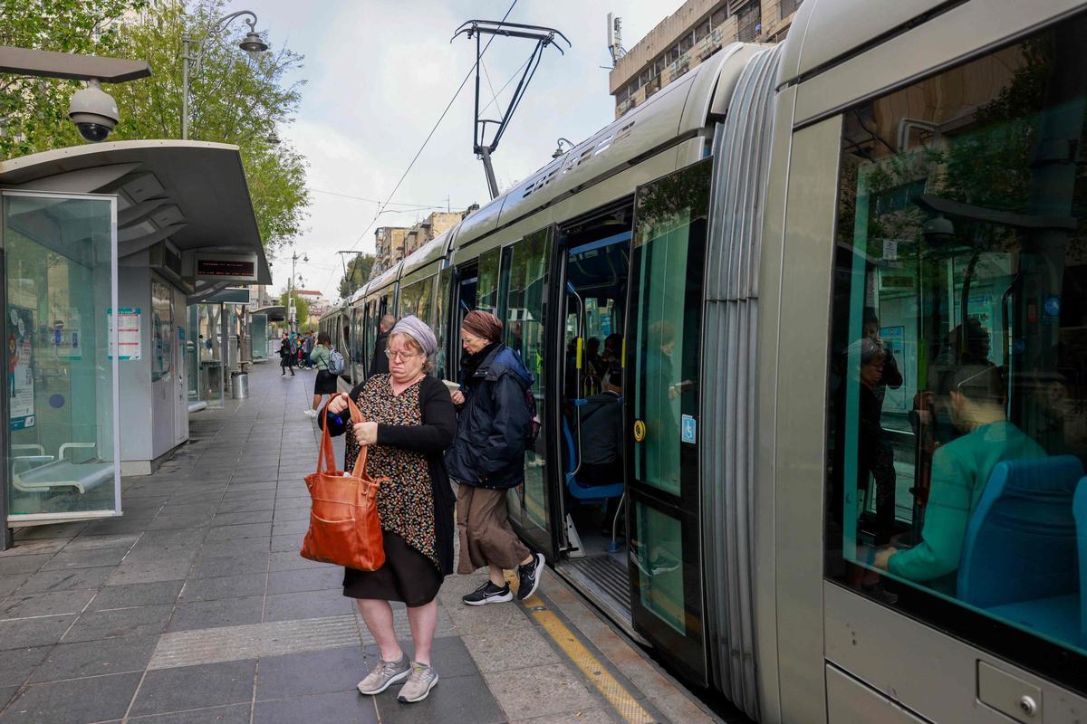 Varios usuarios del tranvía se apean en una estación de Jerusalén.