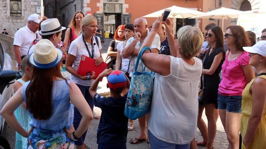 Un grup de turistes amb la seva guia, que porta penjat al coll un micròfon tot i que no hi parla