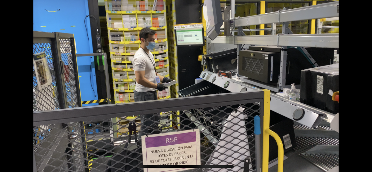 Un empleado de Amazon en El Prat prepara un envío tomando los productos de una estantería robotizada.