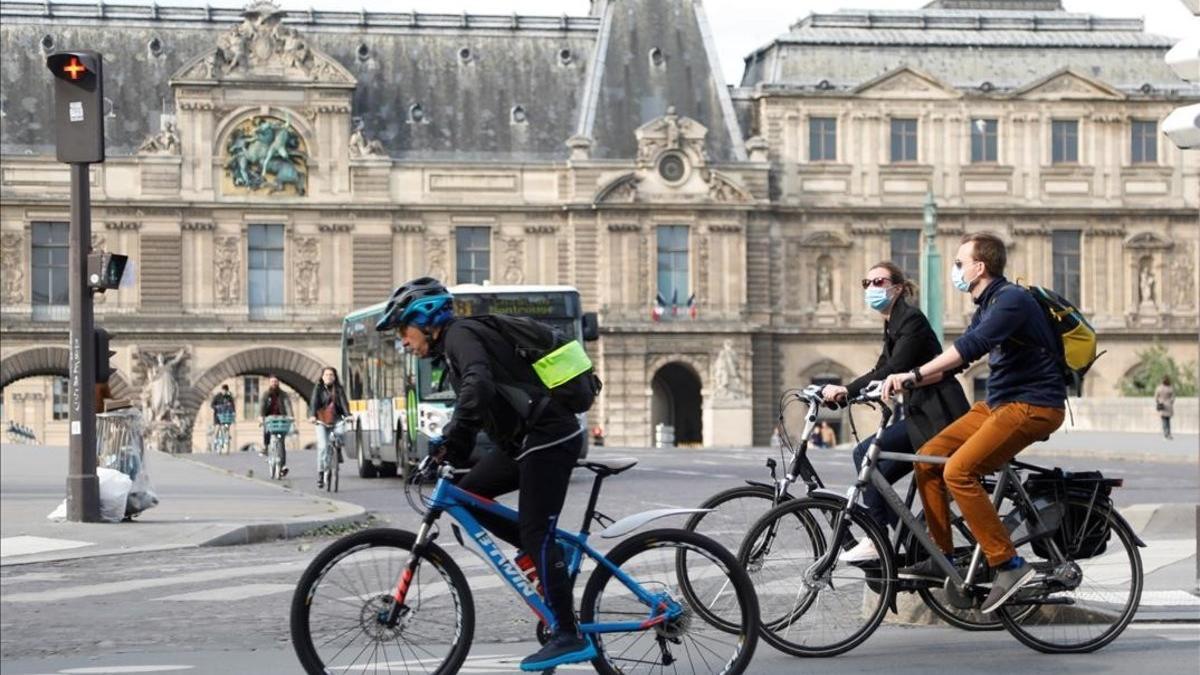 Dos ciclistas en el exterior del museo del Louvre en París.