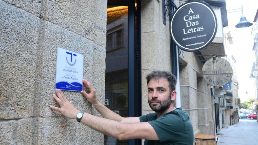 Jesús Portas coloca el cartel con el distintivo de calidad turística en el exterior del establecimiento &quot;A casa das letras&quot;.