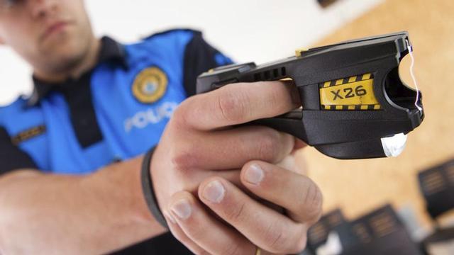 Un agent de la policia sosté una pistola elèctrica. | ANNA MAS