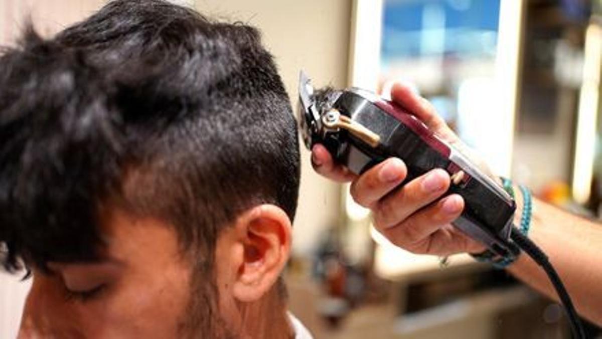 Un chico se corta el pelo en una barbería de Madrid.