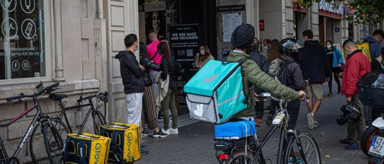 Varios ’riders’ esperan ante un restaurante de Barcelona para recoger pedidos.