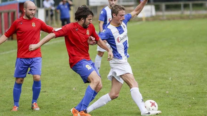 El jugador del Avilés Thomas, con el balón, presionado por Imaz, con Juanín a la izquierda.