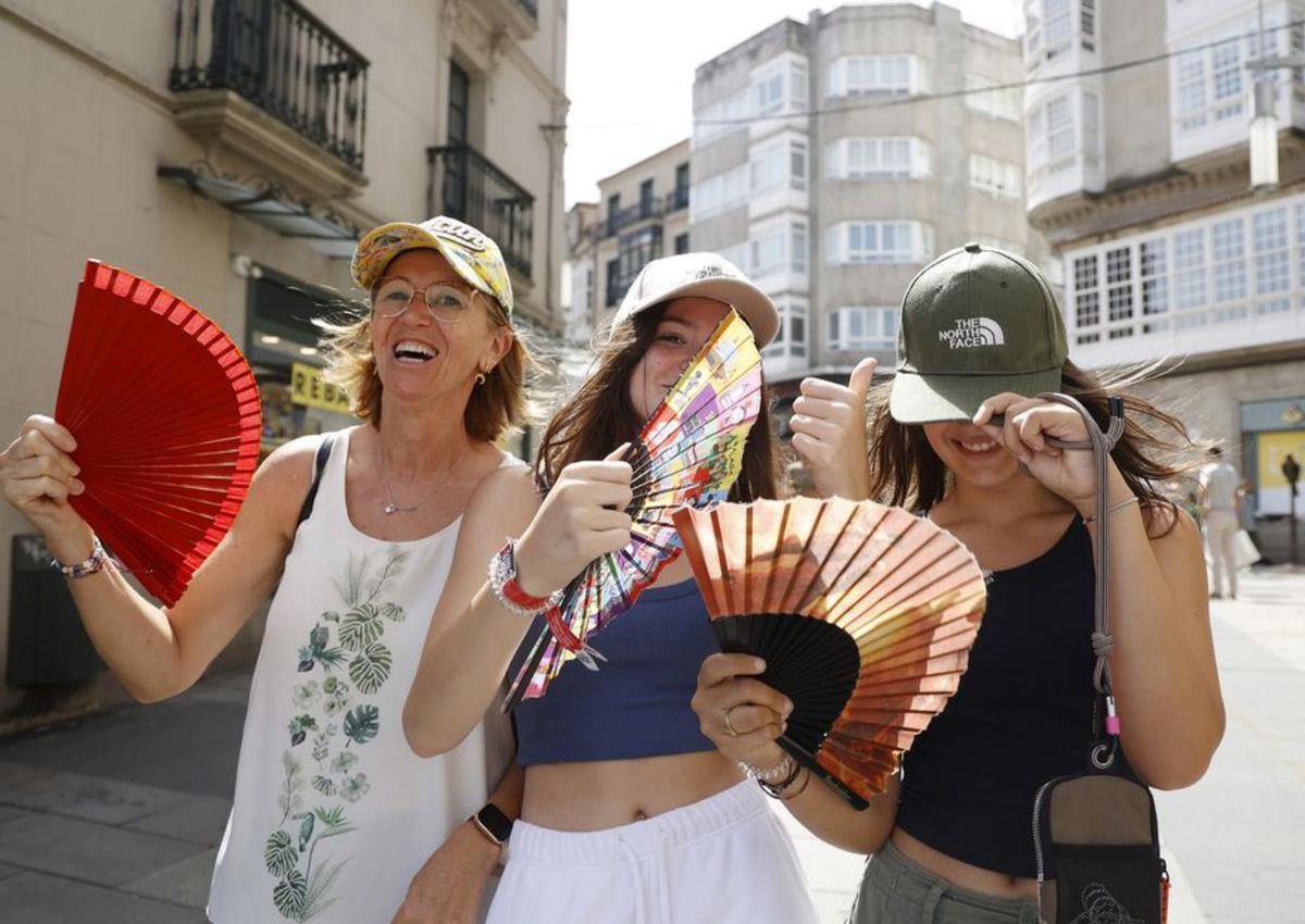 Tres mujeres, con abanicos y viseras por el centro de la ciudad. | // G.S.