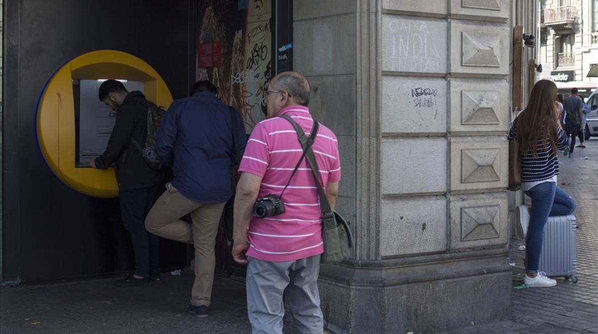 Clientes retiran dinero de un cajero en la plaza de Catalunya. 