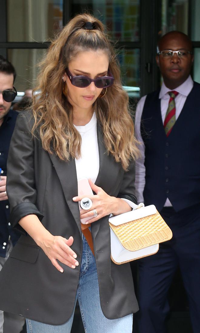 Jessica Alba con chaqueta gris marengo y bolso trenzado