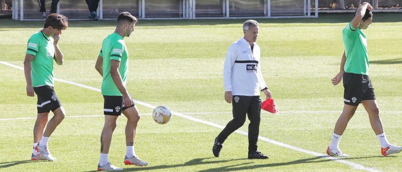 Fran Escribá, con gesto pensativo, pasa entre varios jugadores en el entrenamiento de ayer en el campo de fútbol Díez Iborra. | ANTONIO AMORÓS