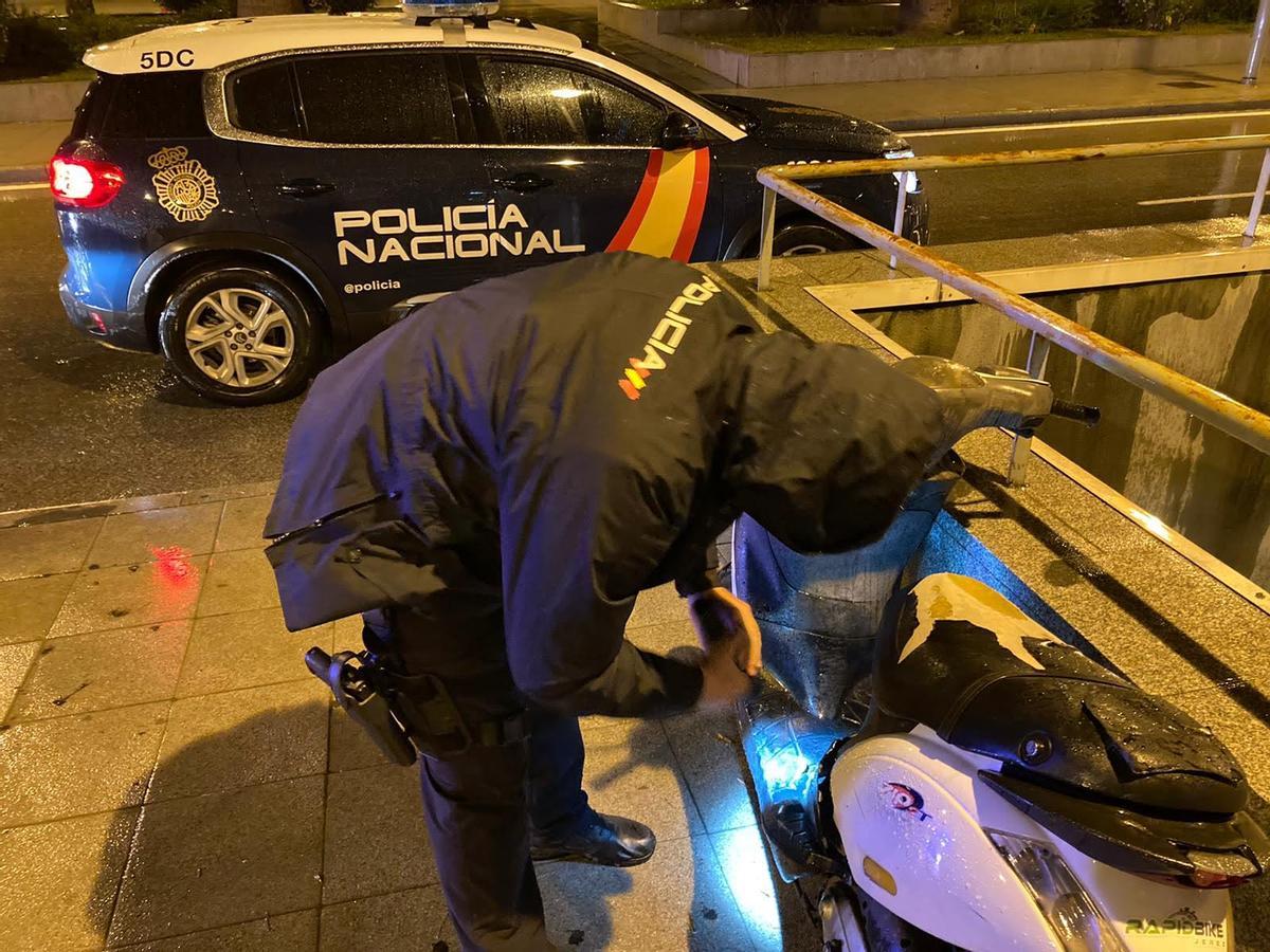 Un policía examina los daños en una moto.