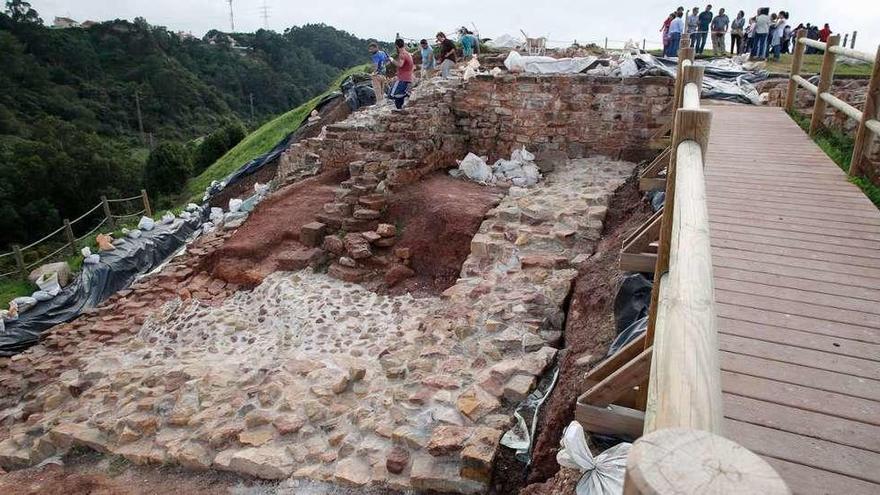 Un grupo de arqueólogos trabajando en el aljibe en la última campaña en 2016 y visitantes en el castillo de Gauzón.