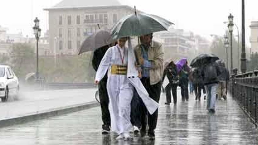 Una nazarena regresa por el puente de Triana bajo la lluvia caída en Sevilla esta Semana Santa.