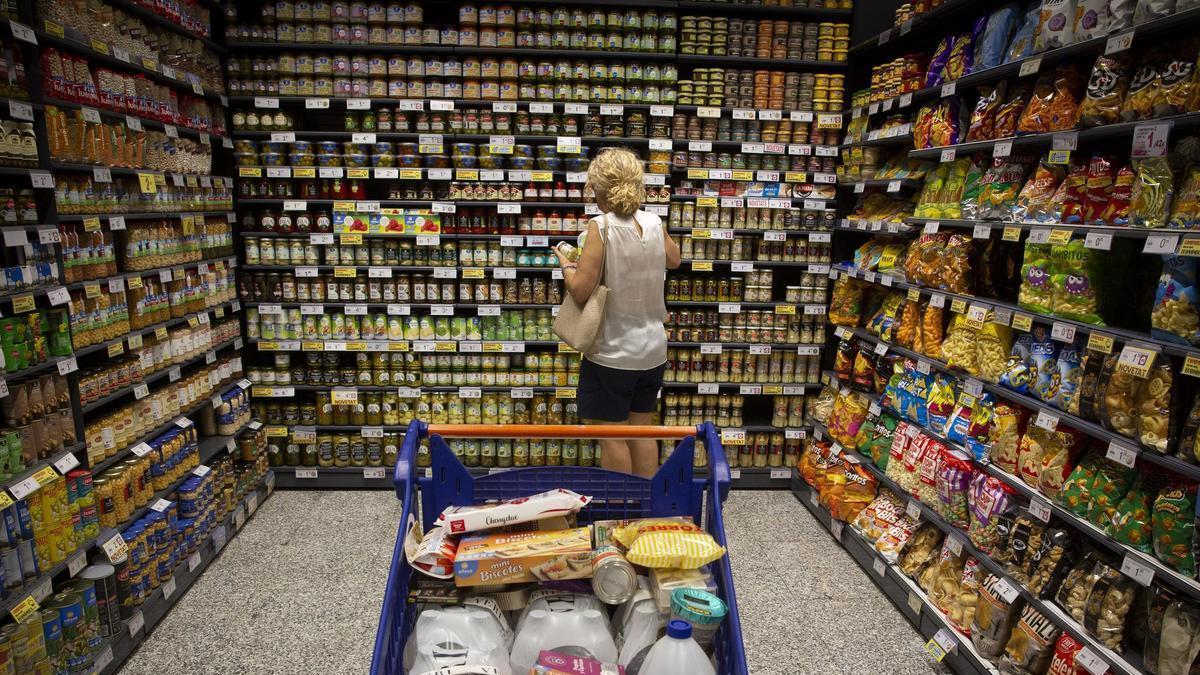 Una mujer junto a su carro de la compra en un supermercado.