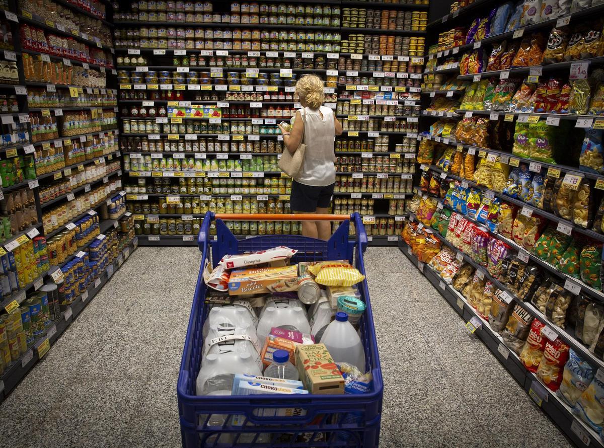 Una mujer junto a su carro de la compra en un supermercado.
