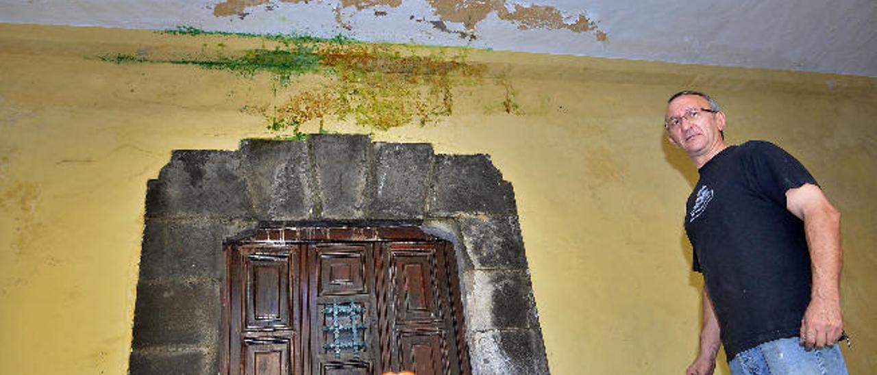 Manolo Fernández, uno de los encargados de El Bodegón, ante una de las puertas con desconchones y humedades.