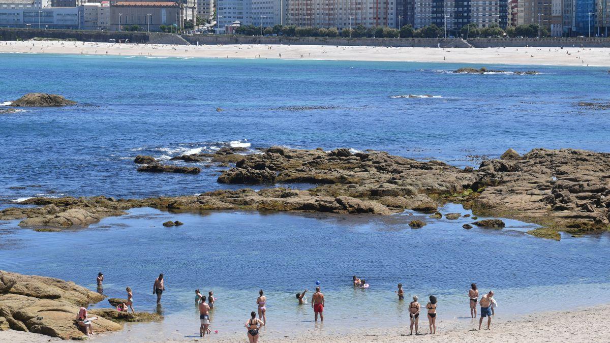 Bañistas en Riazor un día de cielos soleados.
