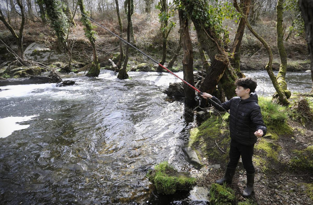 Un niño pesca en el río Asneiro