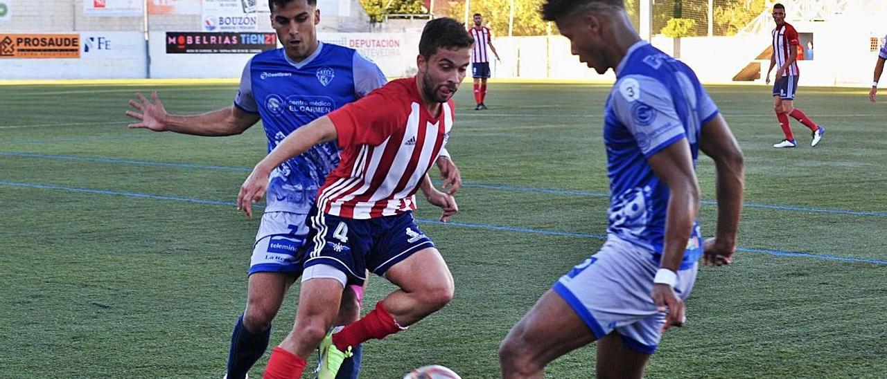 Ube trata de eludir a dos rivales en el partido entre el Alondras y el Ourense CF. |  // RAFA VÁZQUEZ