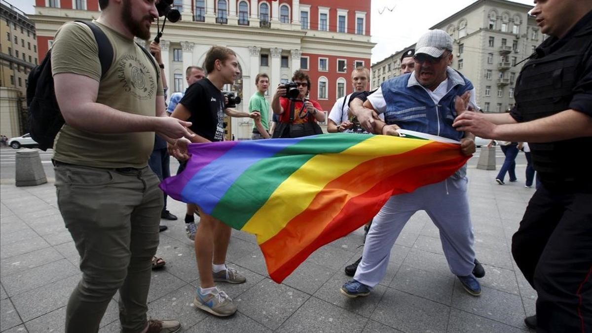 Manifestantes homófobos tratan de romper una bandera gay de un grupo de homosexuales en Moscú.